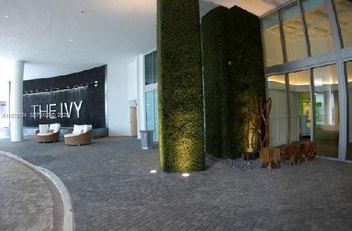 The exterior entrance of a building features a water wall, green pillars, and lounge seating — 90 SW 3 ST # 3210, Miami FL 33130, MIAMI, FL