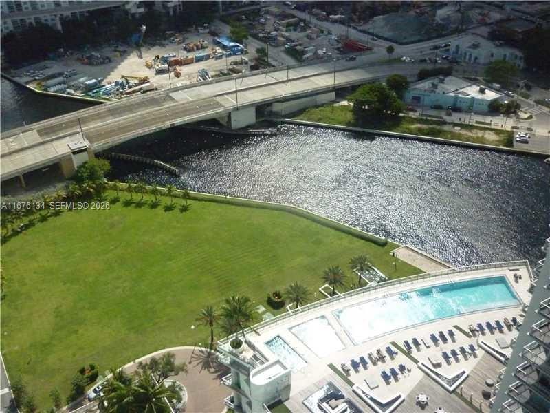 An aerial view shows a swimming pool deck, a large grassy lawn, and a nearby bridge — 90 SW 3 ST # 3210, Miami FL 33130, MIAMI, FL