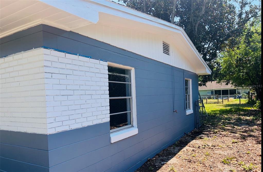 The exterior of a house features blue horizontal siding, white brick accents, and two windows — 2214 Ave B SW SW 2214 AVE B SW, WINTER HAVEN, FL