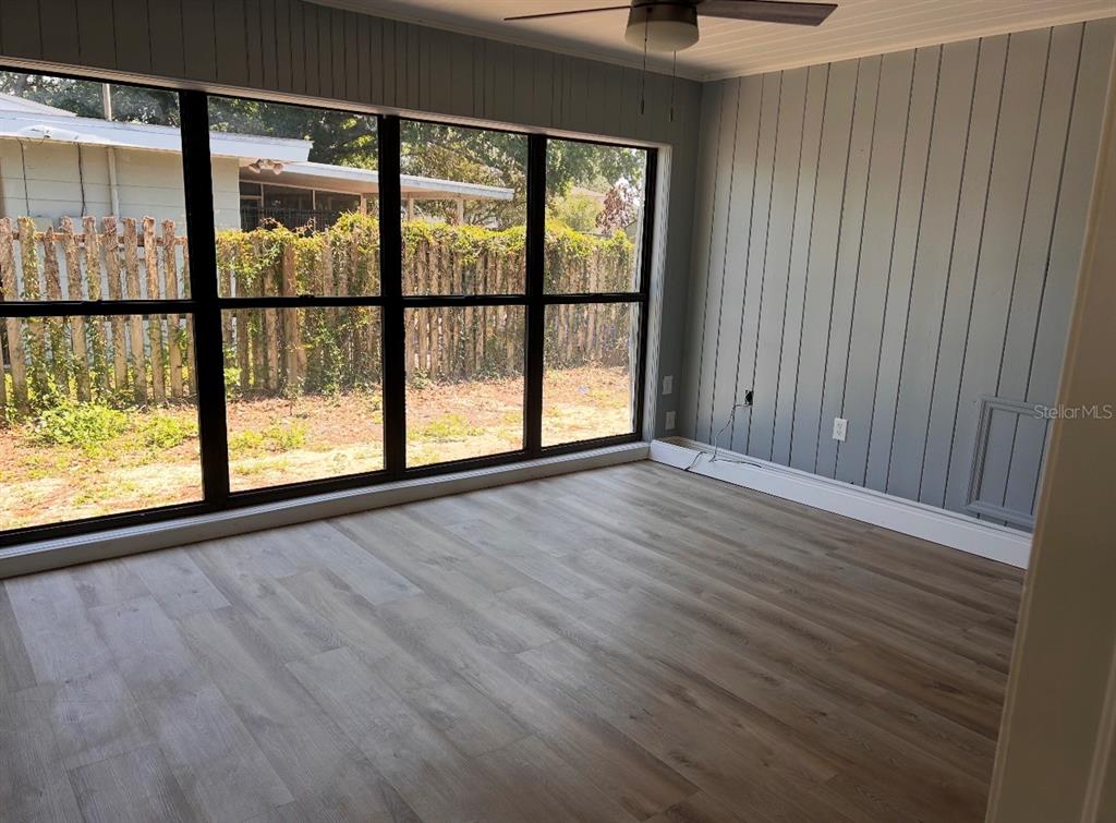 A room with light wood-look flooring, gray vertical paneled walls, and a large window wall — 2214 Ave B SW SW 2214 AVE B SW, WINTER HAVEN, FL