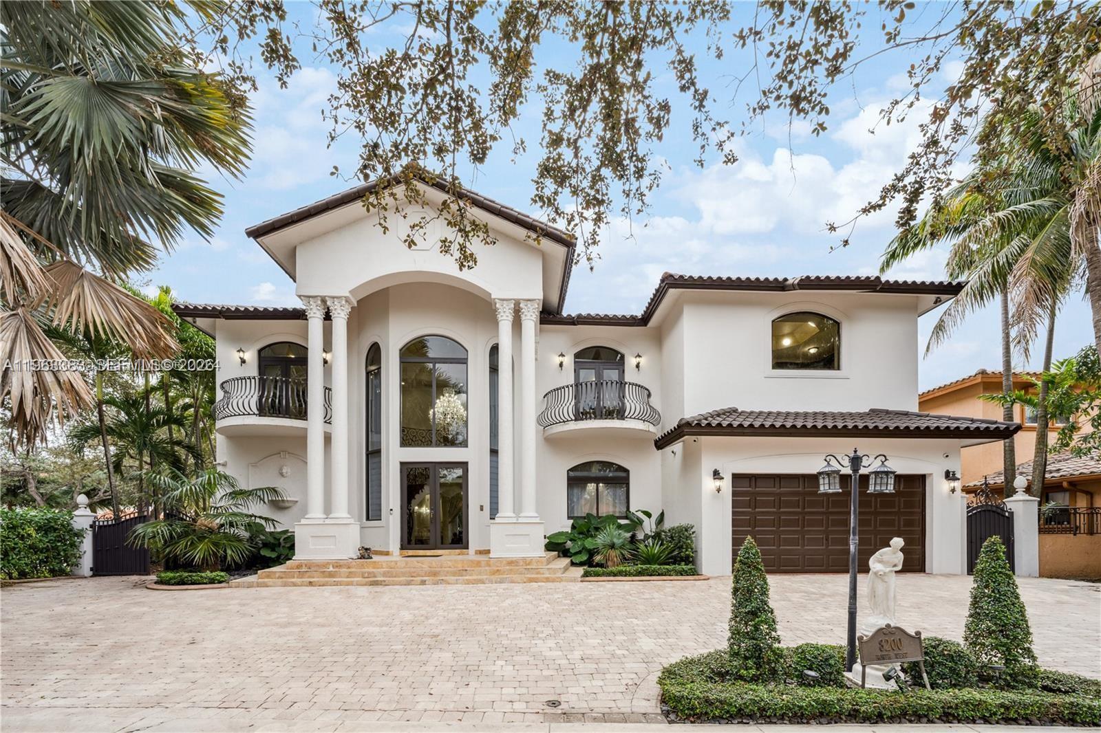 A two-story Mediterranean-style house features a grand columned entrance, balconies, and a paved driveway — 8200 NW 163rd St, Miami Lakes FL 33016, MIAMI LAKES, FL