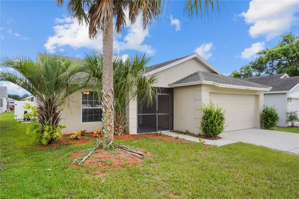A single-story house with a beige stucco exterior, a two-car garage, and a screened entryway — 1513 INDIAN OAKS TRAIL, KISSIMMEE, FL