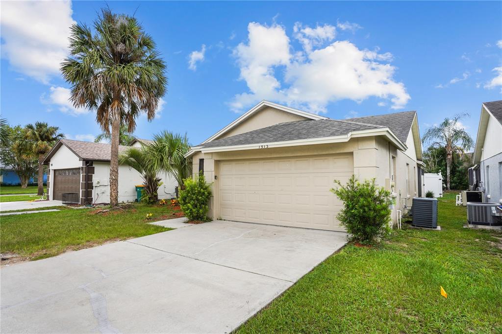 A single-story house with a beige stucco exterior, a two-car garage, and a palm tree — 1513 INDIAN OAKS TRAIL, KISSIMMEE, FL