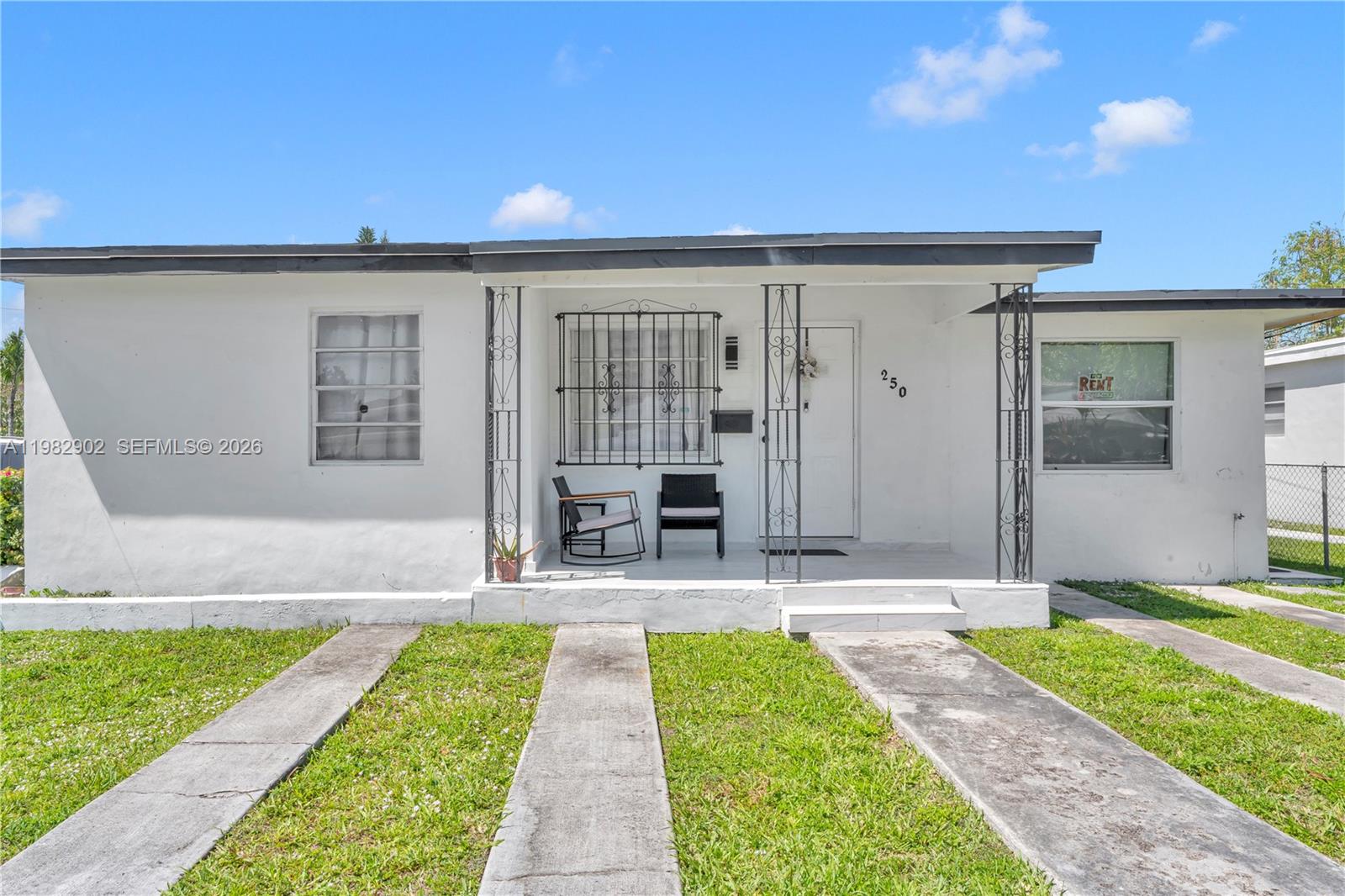 A white single-story house features a covered front porch with iron supports and metal grilles — 250 NW 34th Ave, Miami FL 33125, MIAMI, FL