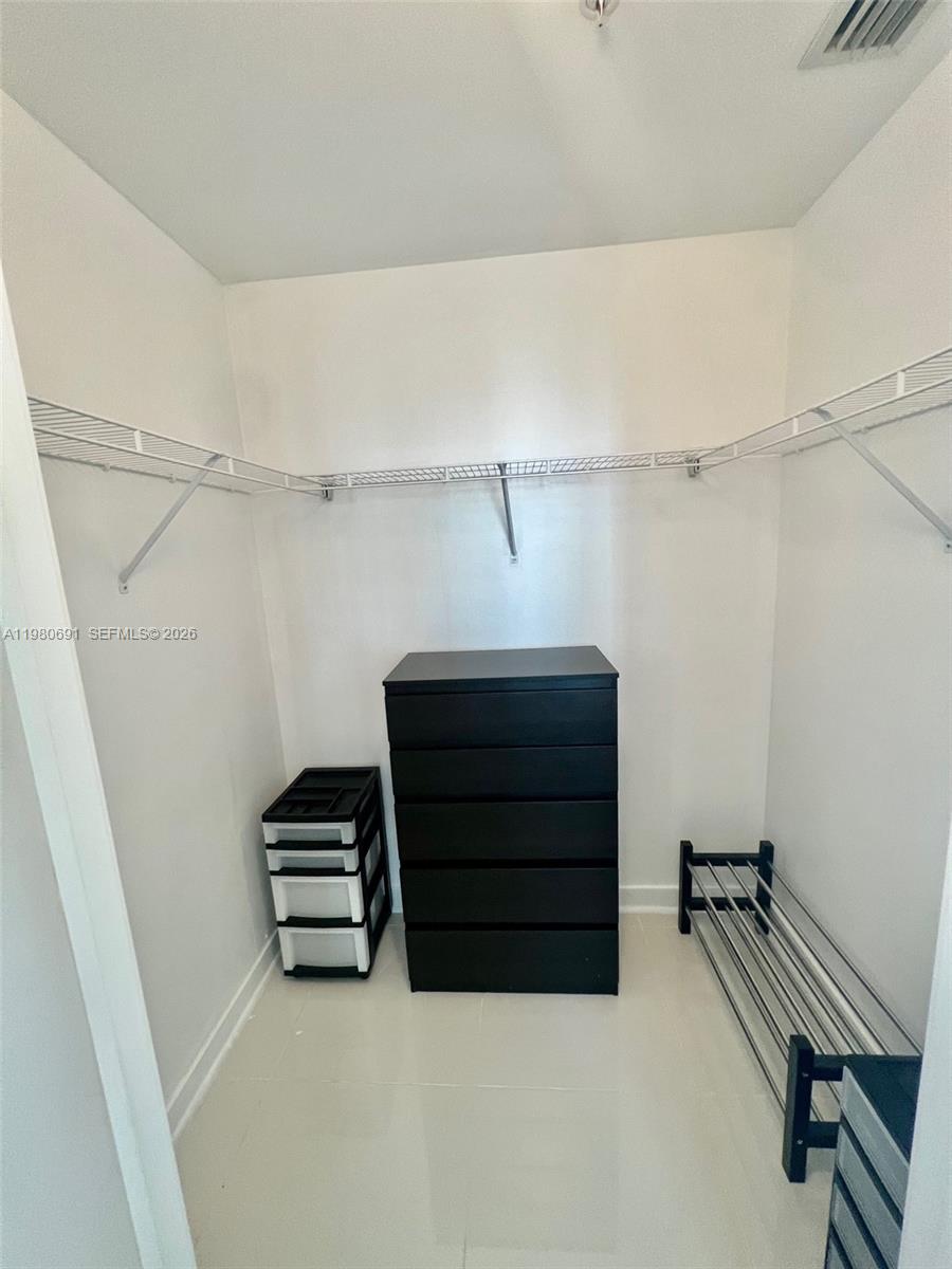 A walk-in closet features white walls, wire shelving, a black dresser, and a shoe rack — 1111 SW 1st Ave # 3223, Miami FL 33130, MIAMI, FL