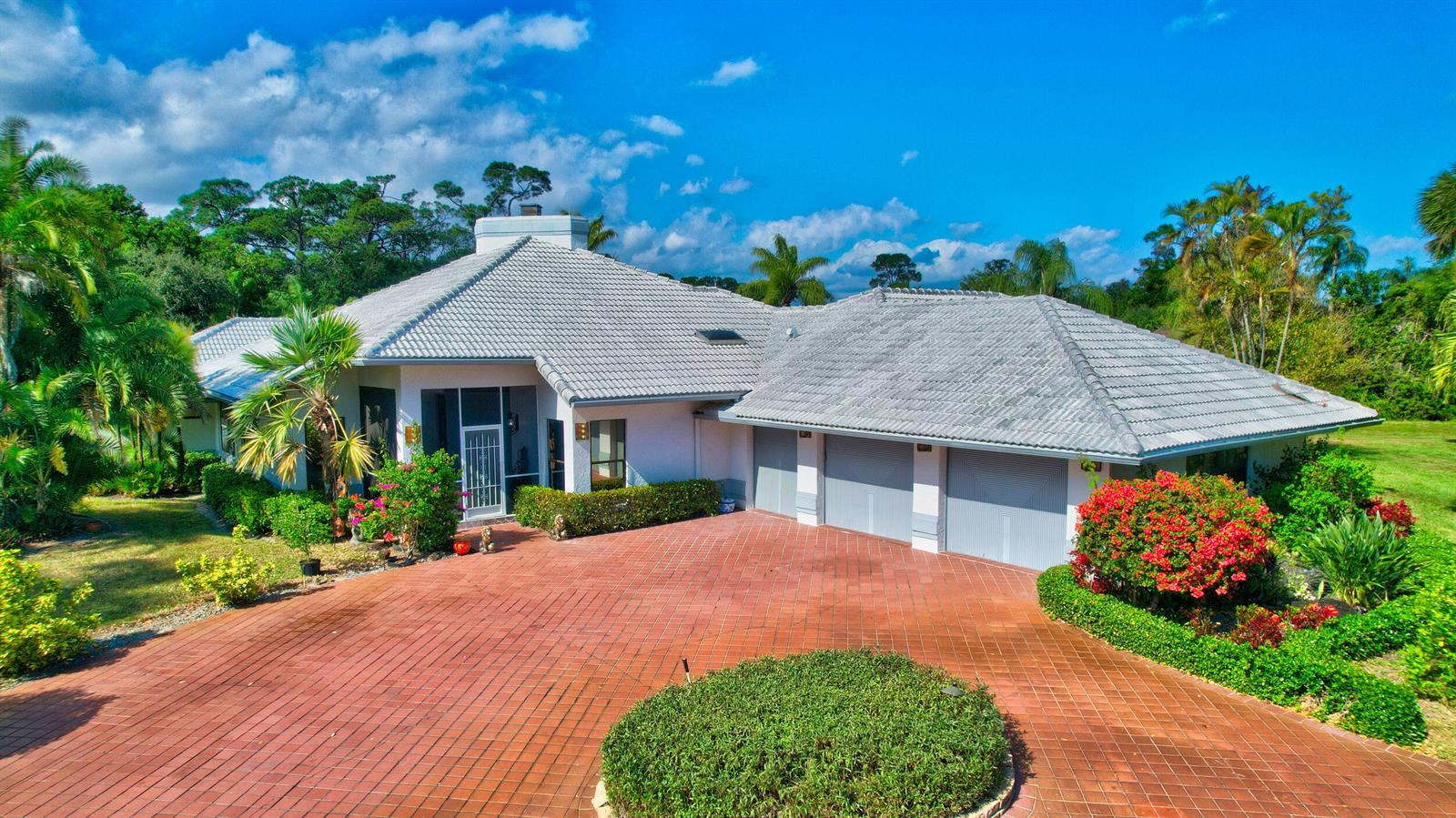 A single-story house with a tiled roof, three-car garage, and a red brick driveway — 56 Northwoods Lane, Boynton Beach FL 33436, BOYNTON BEACH, FL