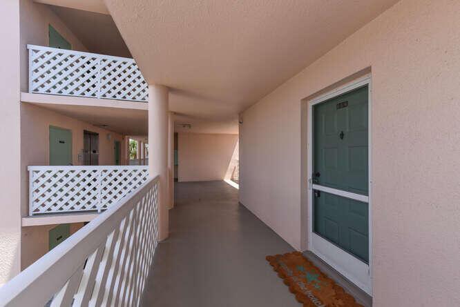 An exterior apartment hallway features a green door, a welcome mat, and white lattice railings — 353 S Us Highway 1 # F306, Jupiter FL 33477, JUPITER, FL