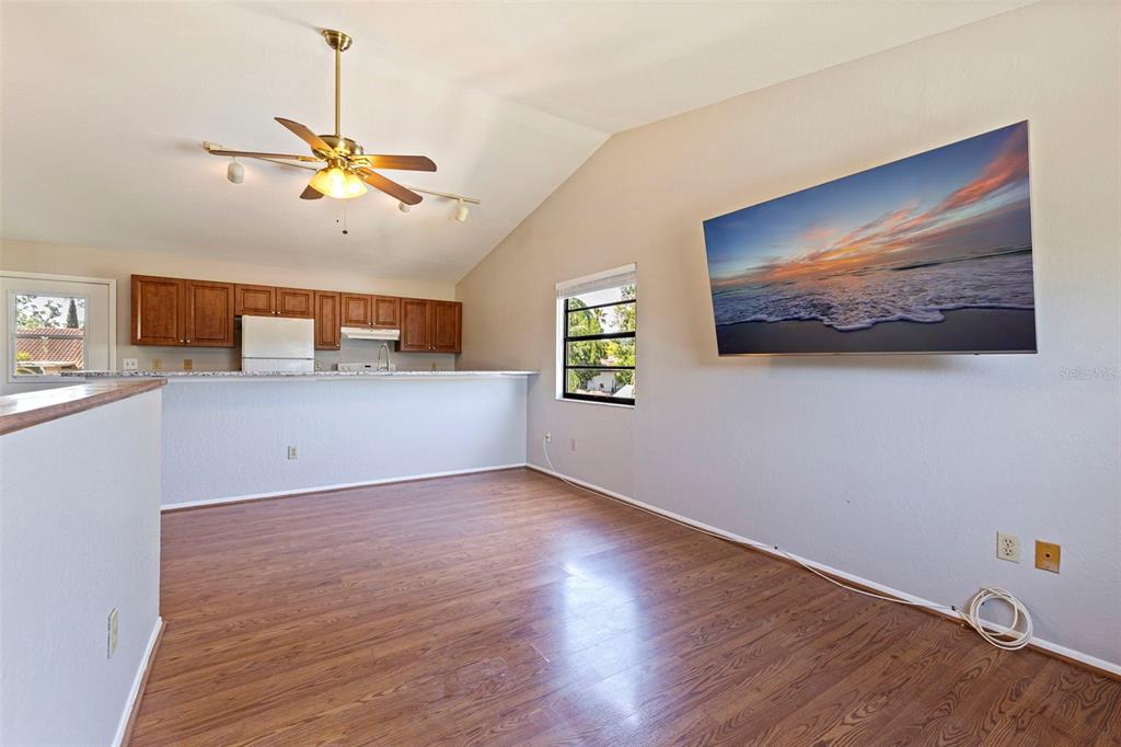 A living room with wood-look flooring, a vaulted ceiling, and a wall-mounted television — 334 CROSSWINDS DRIVE, PALM HARBOR, FL