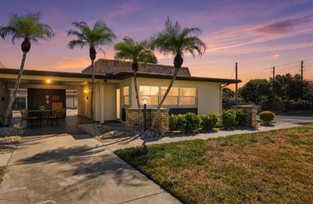A single-story house with a carport, palm trees, and brick accents at sunset — 5153 TURQUOISE LANE UNIT 102, NEW PORT RICHEY, FL