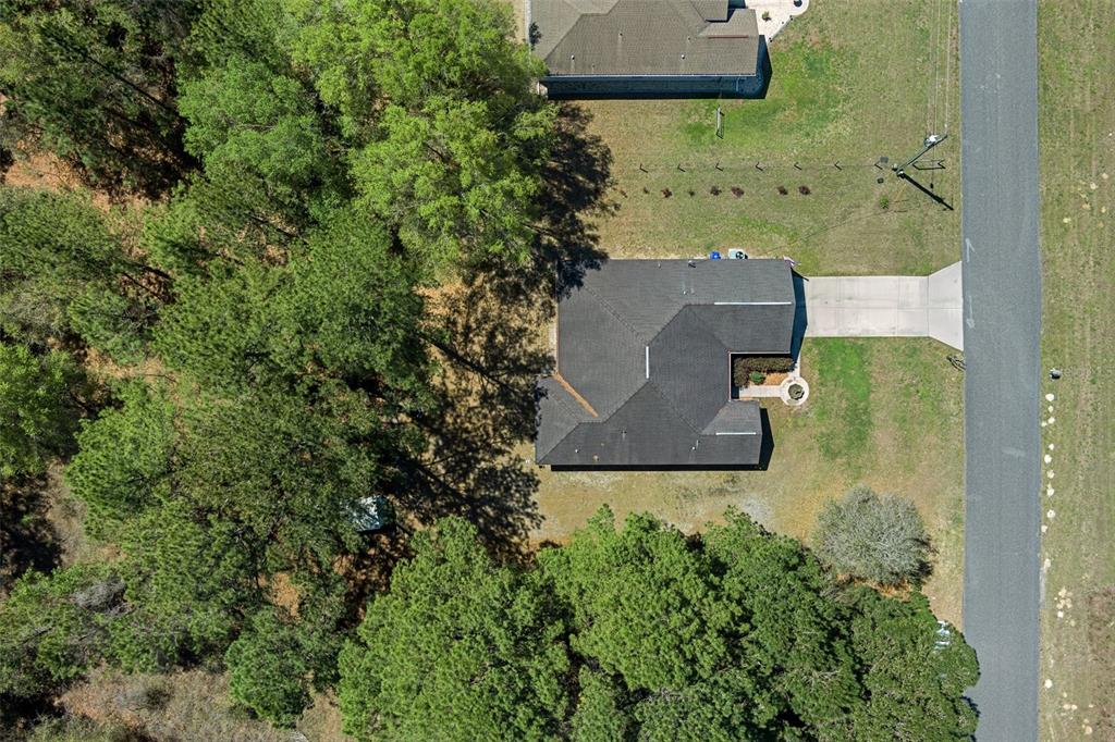 An aerial view shows a single-story house with a dark roof surrounded by trees — 8623 N DORA WAY, DUNNELLON, FL