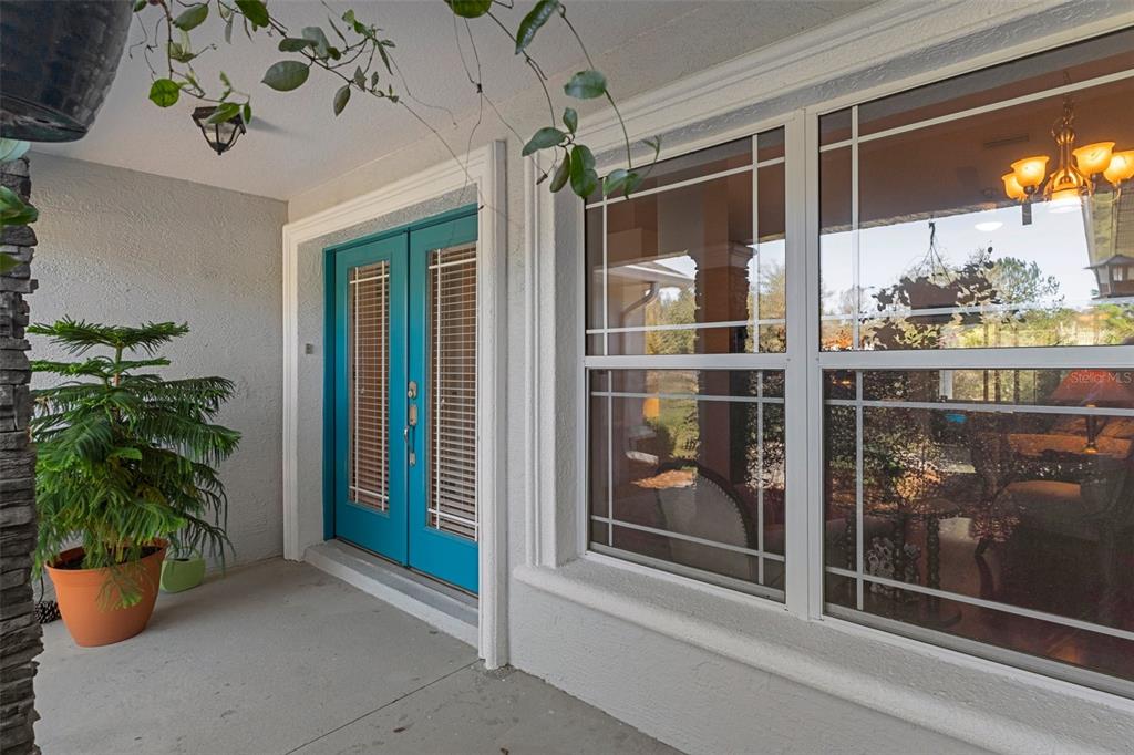 A covered porch features a teal double door and a large window with white trim — 8623 N DORA WAY, DUNNELLON, FL