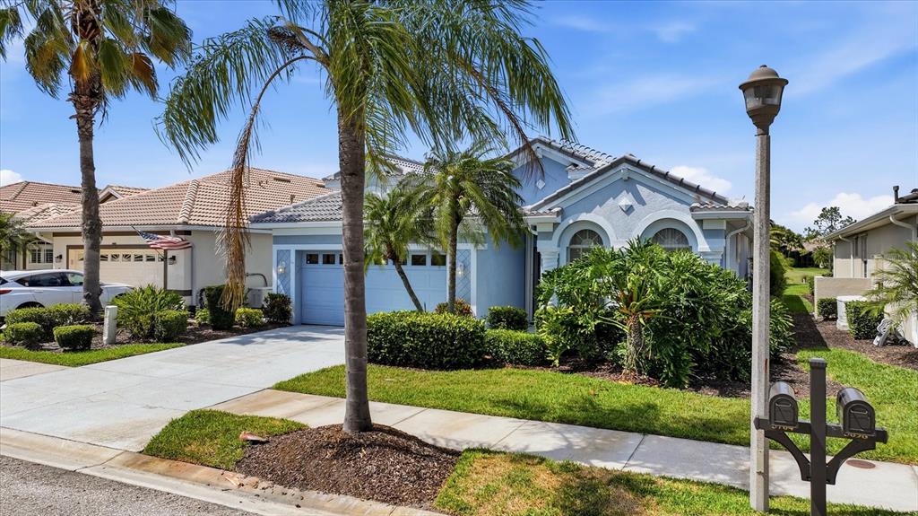 A light blue single-story house with a two-car garage, palm trees, and a front lawn — 5704 WHITE JASMINE WAY, NORTH PORT, FL
