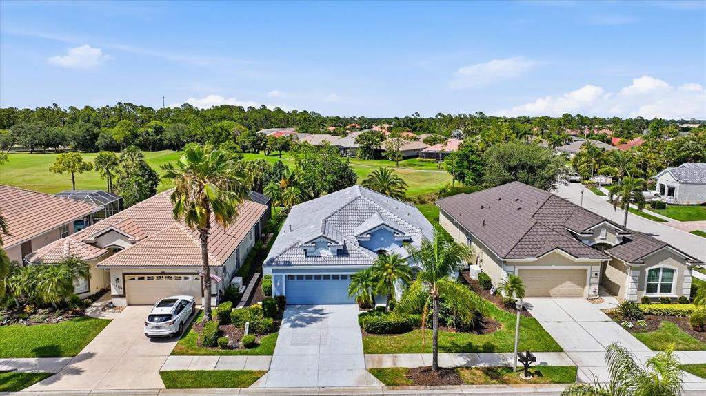 An aerial view shows three suburban houses with tiled roofs and driveways near a golf course — 5704 WHITE JASMINE WAY, NORTH PORT, FL