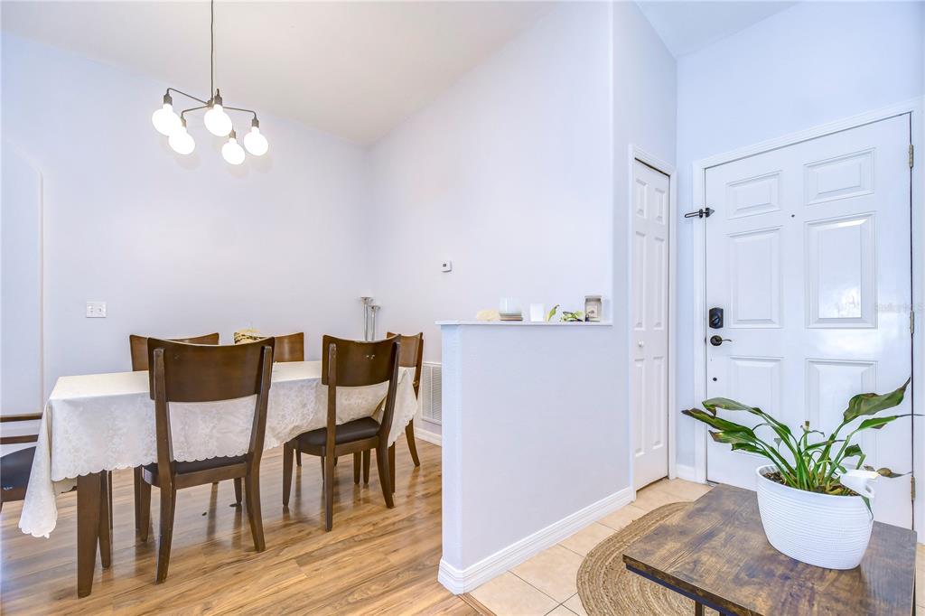 A dining area with a wooden table and chairs sits beside a white entry door — 30847 BRIDGEGATE DRIVE, WESLEY CHAPEL, FL