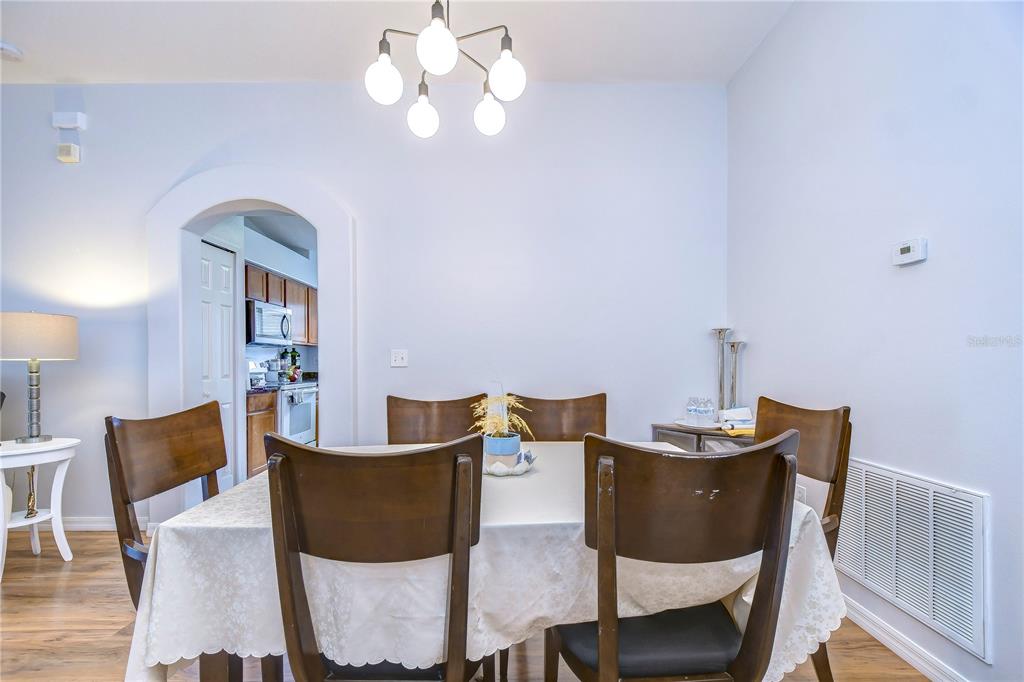 A dining room features a table with six chairs, a chandelier, and an arched doorway — 30847 BRIDGEGATE DRIVE, WESLEY CHAPEL, FL