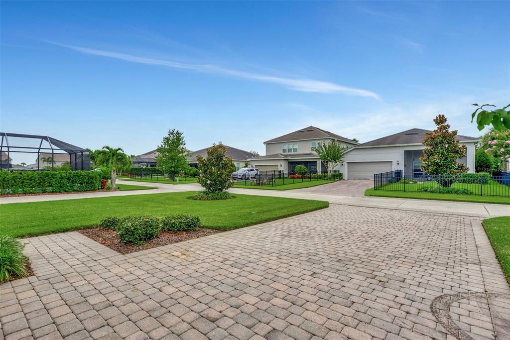 A paved driveway leads to a suburban house with a lawn and black metal fencing — 11616 GOLDEN BAY PLACE, LAKEWOOD RANCH, FL