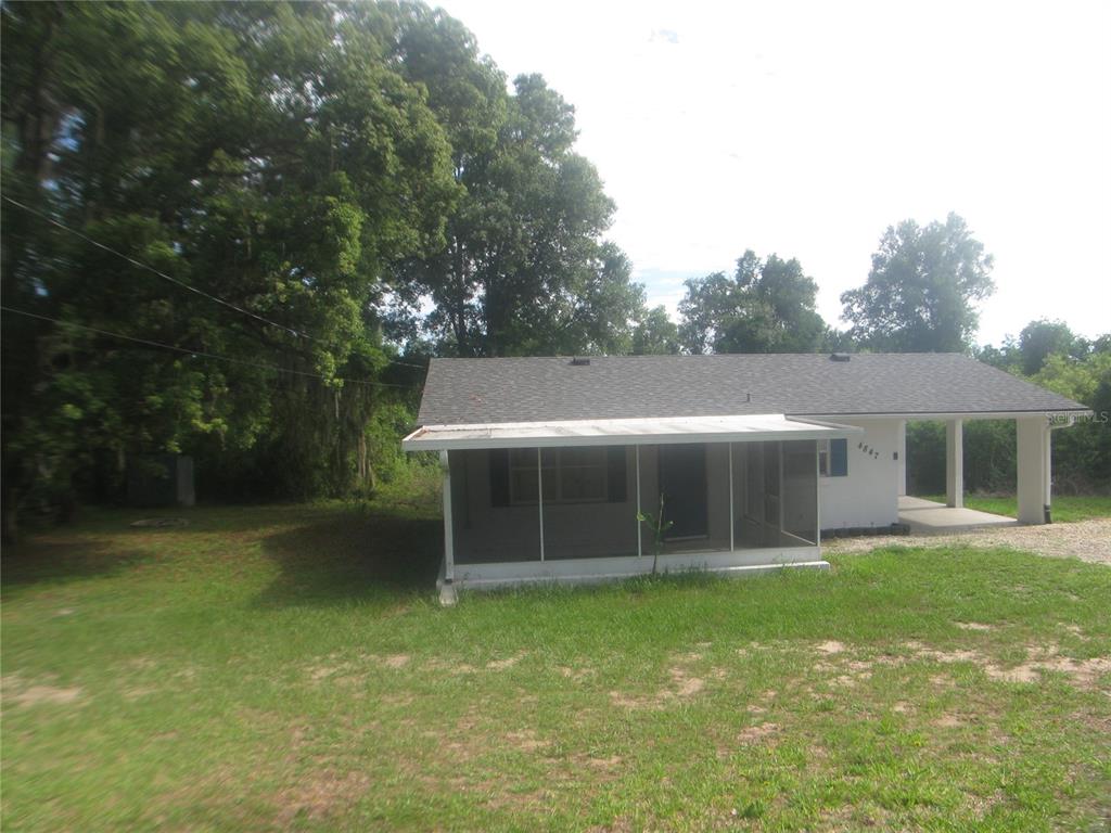 A white single-story house features a screened front porch and an attached carport — 4847 EAGLES NEST ROAD, FRUITLAND PARK, FL