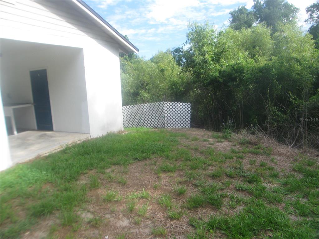 A white house exterior with a covered patio and a white lattice fence in the yard — 4847 EAGLES NEST ROAD, FRUITLAND PARK, FL