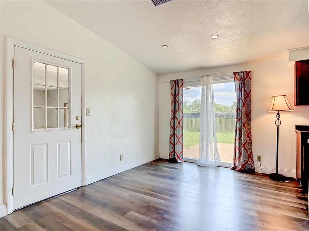 A room with wood-look flooring, a white door, and sliding glass doors leading outside — 943 MONROE HARBOR PLACE, SANFORD, FL