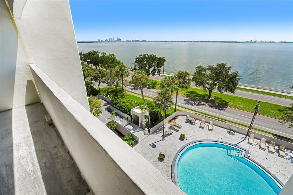 A high-angle view from a balcony overlooking a swimming pool, a road, and the ocean — 4141 BAYSHORE BOULEVARD UNIT 602, TAMPA, FL
