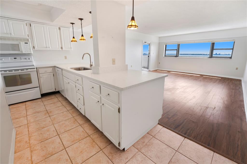 A white kitchen with tile flooring opens into a living area with wood-look floors — 4141 BAYSHORE BOULEVARD UNIT 602, TAMPA, FL