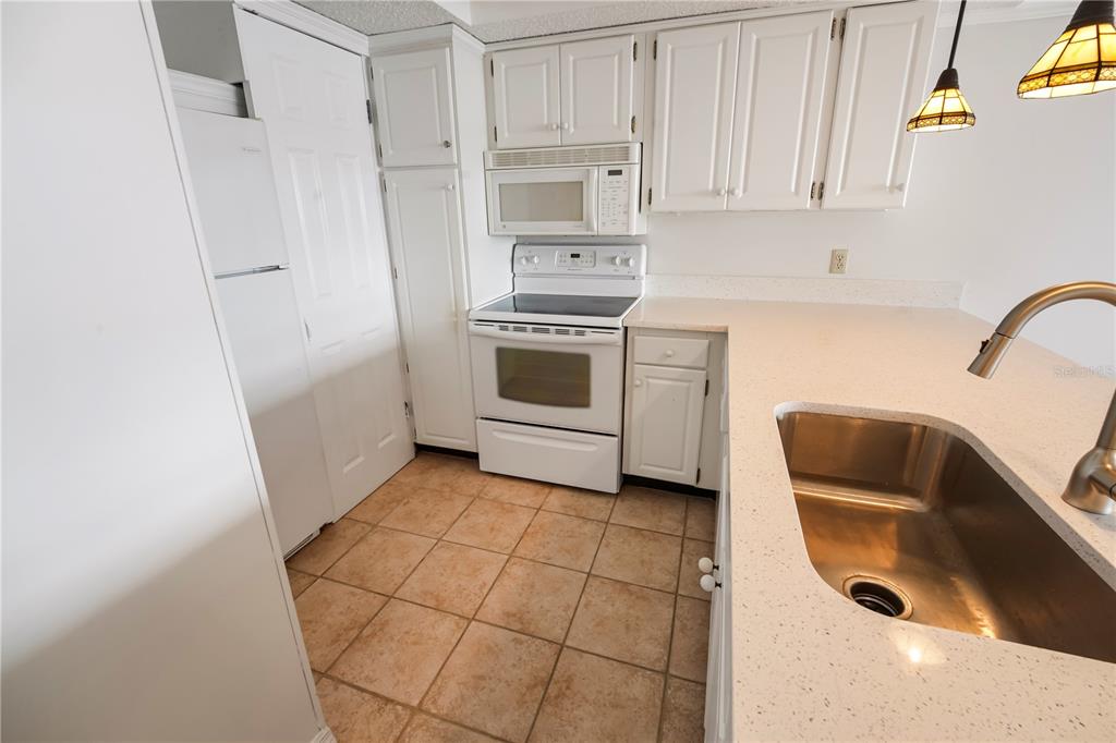 A kitchen features white cabinets, a white stove, a stainless steel sink, and tiled flooring — 4141 BAYSHORE BOULEVARD UNIT 602, TAMPA, FL