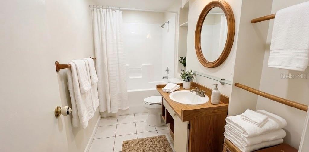 A bathroom features a wooden vanity, a round mirror, and a white shower-tub combination — 1221 SE 24TH ROAD, OCALA, FL