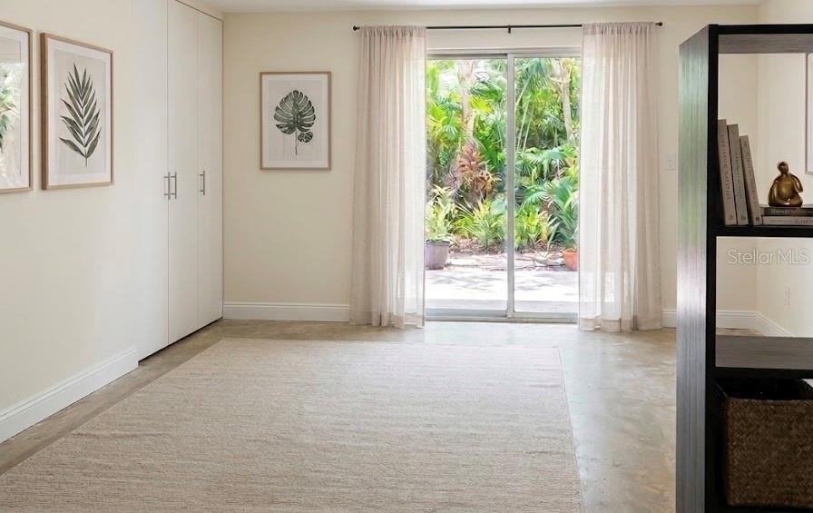 A bright room features a beige rug, white closets, wall art, and a sliding glass door — 1221 SE 24TH ROAD, OCALA, FL