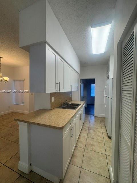 A kitchen features white cabinets, tan countertops, and tile flooring — 18336 NW 68th Ave # C, Hialeah FL 33015, HIALEAH, FL