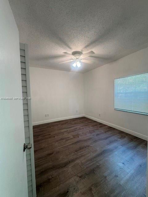 An empty bedroom features dark wood-look flooring, white walls, and a ceiling fan — 18336 NW 68th Ave # C, Hialeah FL 33015, HIALEAH, FL