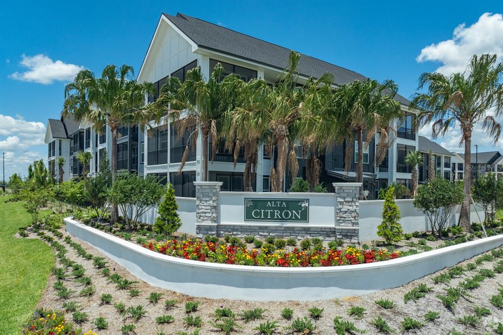 A multi-story apartment building with a stone monument sign in front of palm trees — 3020 BASE BOULEVARD UNIT C1, DAVENPORT, FL