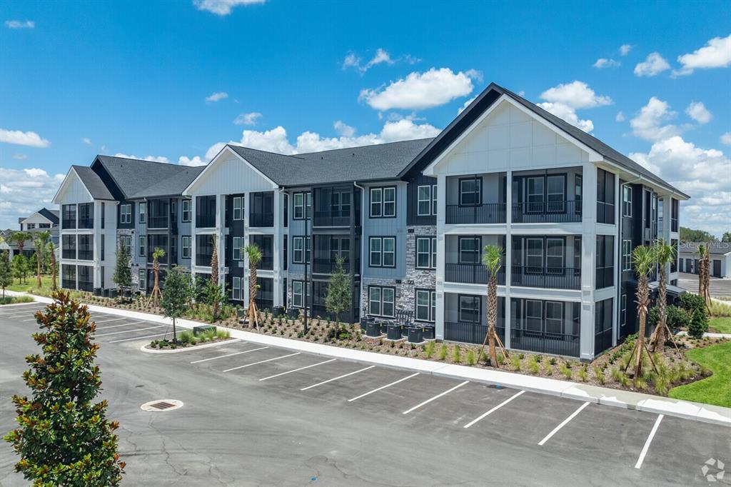 A multi-story apartment building with a parking lot in the foreground under a blue sky — 3020 BASE BOULEVARD UNIT C1, DAVENPORT, FL