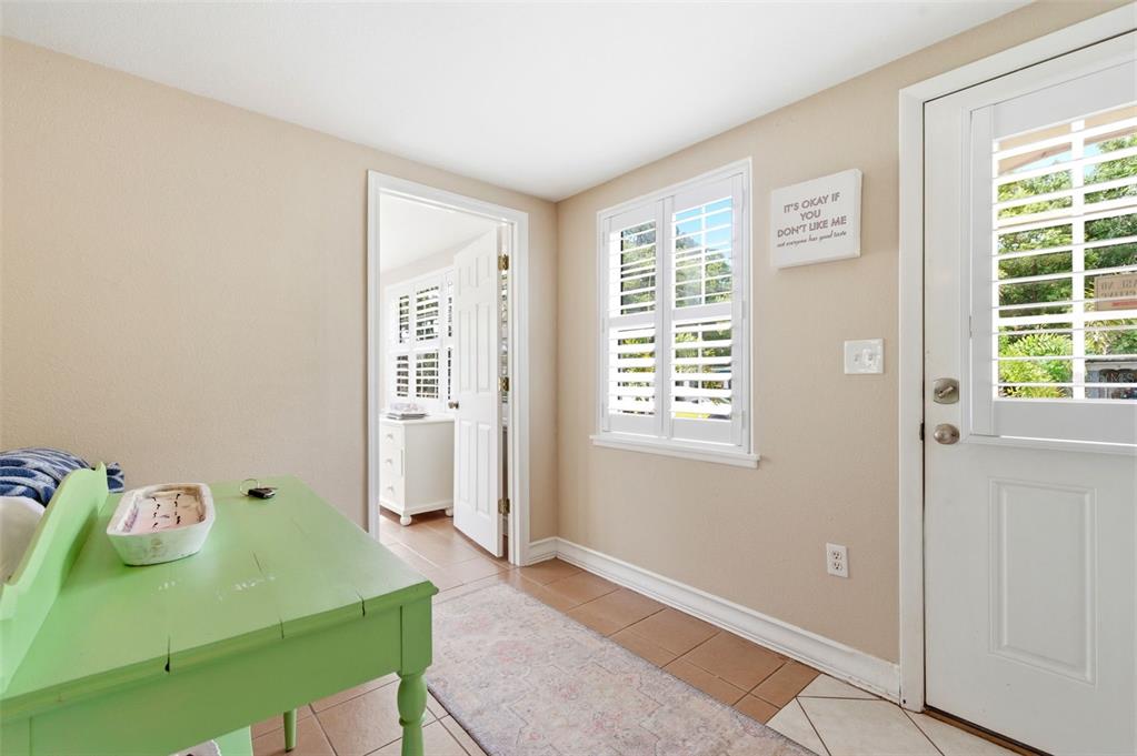 A bright entryway features a green desk, tile flooring, a window with shutters, and a door — 652 LEXINGTON STREET, DUNEDIN, FL