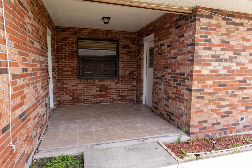A covered brick porch features tiled flooring, a window, and two white doors — 661 LAKE CAROLYN CIRCLE, LAKELAND, FL