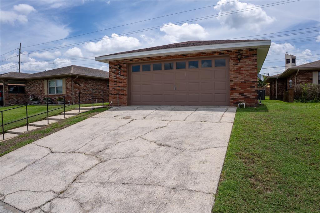 A brick house with a brown garage door and a cracked concrete driveway — 661 LAKE CAROLYN CIRCLE, LAKELAND, FL