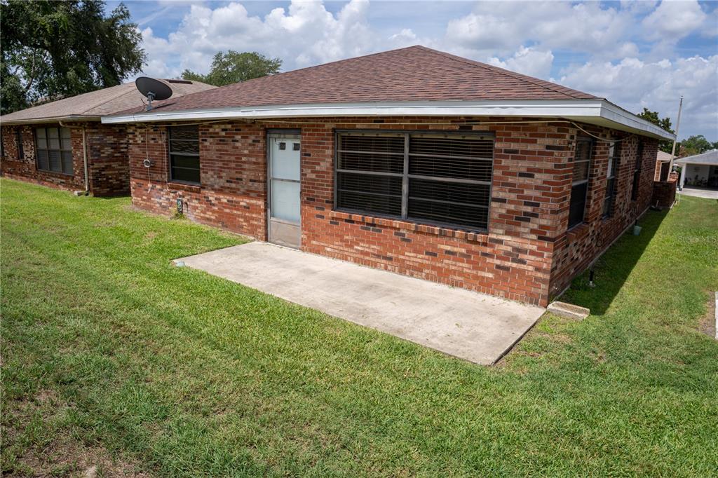 The exterior of a brick house features a concrete patio and a screen door — 661 LAKE CAROLYN CIRCLE, LAKELAND, FL