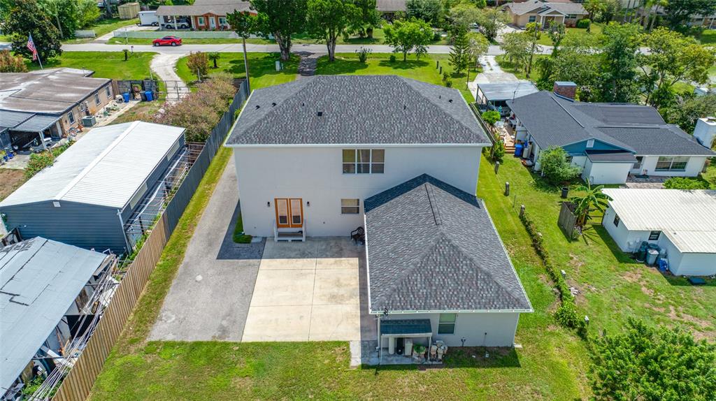An aerial view shows the back of a two-story house with a concrete patio — 13030 DELWOOD ROAD, TAMPA, FL