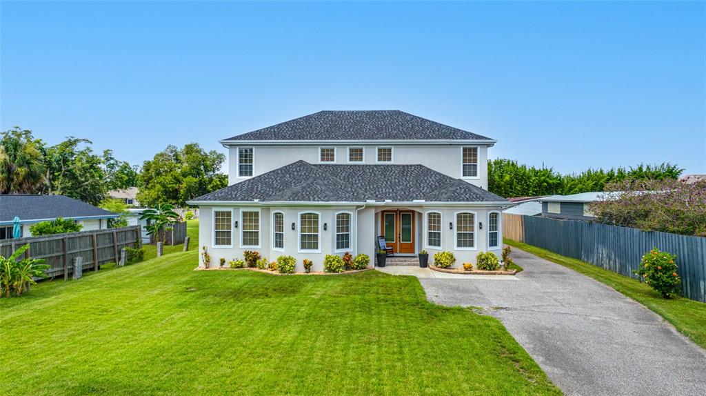 A two-story house with a gray shingled roof, light-colored siding, and a paved driveway — 13030 DELWOOD ROAD, TAMPA, FL