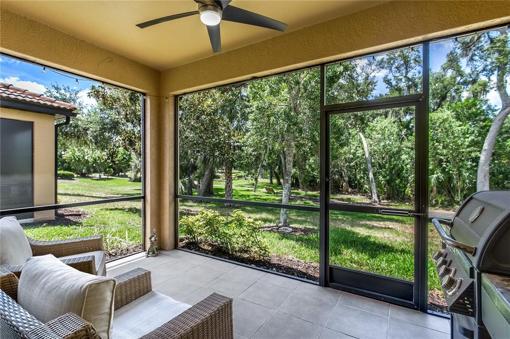 A screened-in patio with tile flooring, wicker furniture, a ceiling fan, and a grill — 312 SENECA FALLS DRIVE, APOLLO BEACH, FL