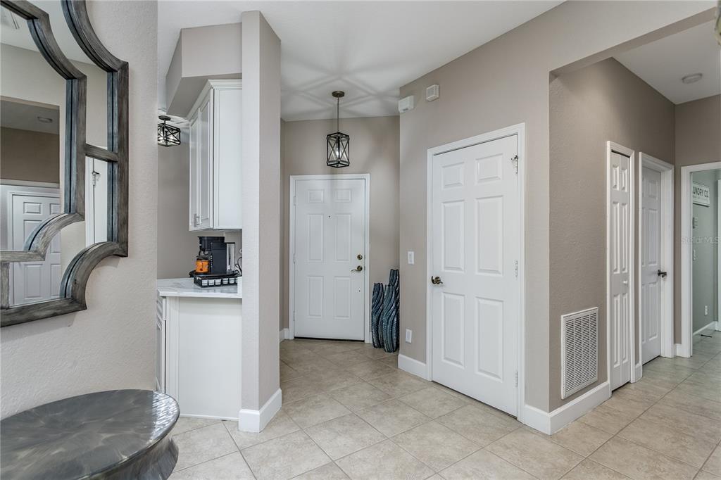 An entryway features tile flooring, a white front door, a coffee station, and interior doors — 312 SENECA FALLS DRIVE, APOLLO BEACH, FL