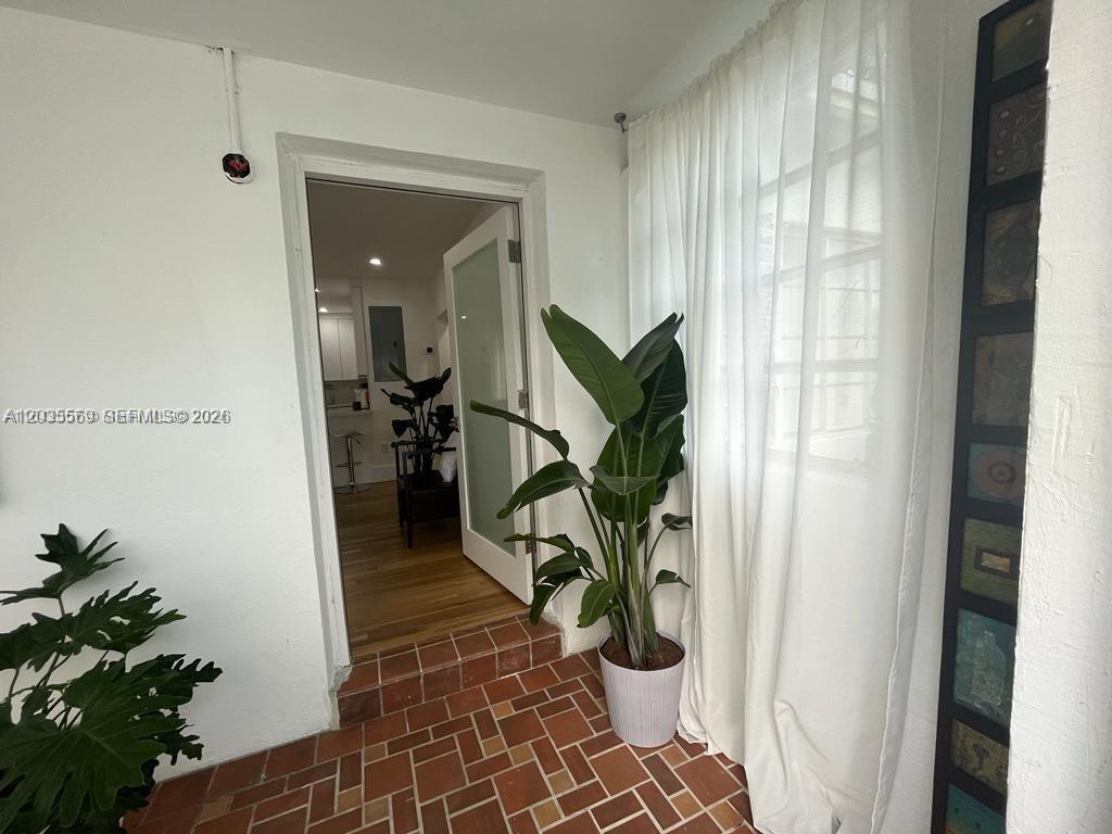 A sunroom with a terracotta tile floor leads through a doorway into a kitchen — 1091 NW 59th St, Miami FL 33127, MIAMI, FL