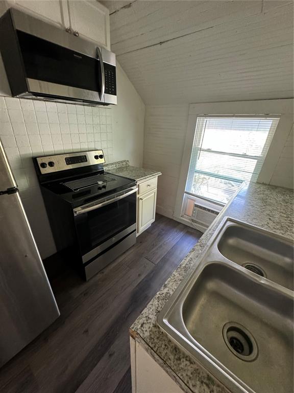 A kitchen features stainless steel appliances, granite countertops, a double sink, and wood-look flooring — 7306 EARLWOOD AVENUE UNIT 2, MOUNT DORA, FL