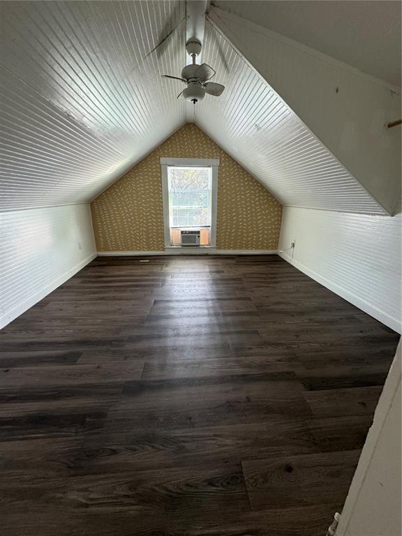 An attic bedroom features white beadboard walls, a yellow patterned accent wall, and dark flooring — 7306 EARLWOOD AVENUE UNIT 2, MOUNT DORA, FL