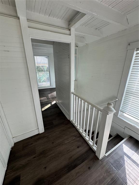 A hallway with dark wood-look flooring leads to a doorway next to a wooden staircase — 7306 EARLWOOD AVENUE UNIT 2, MOUNT DORA, FL
