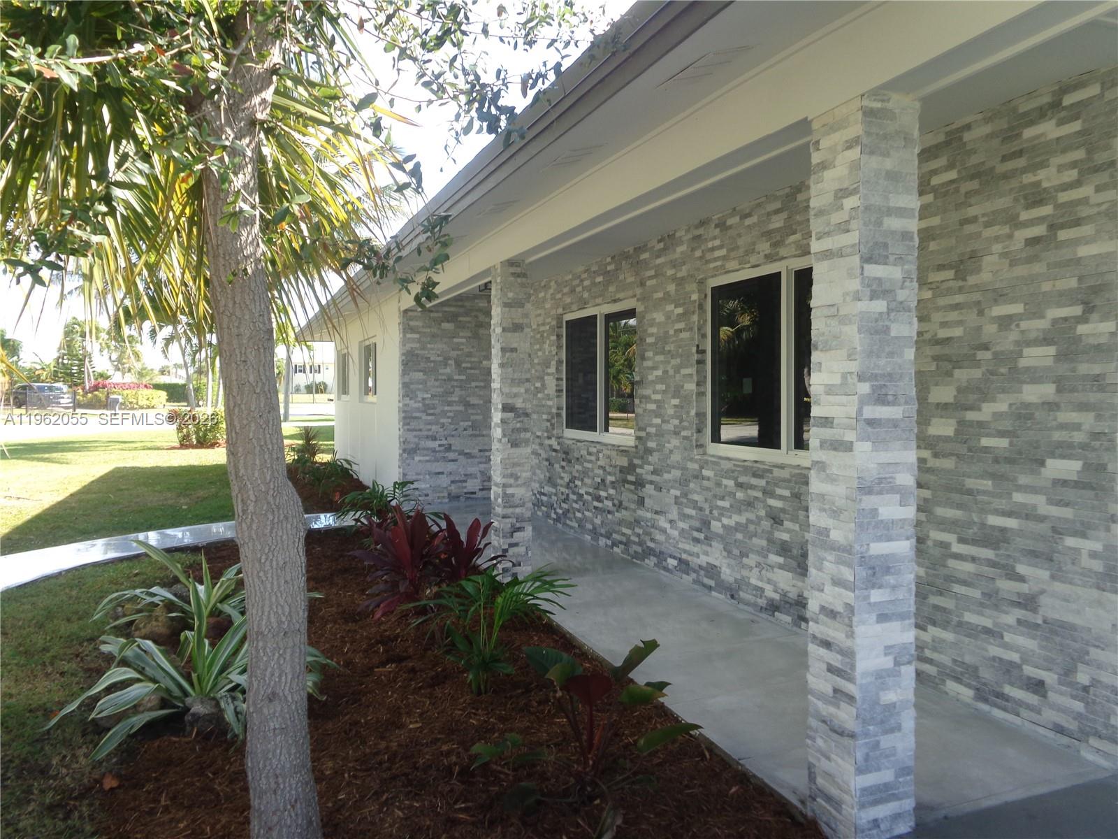 A stone-clad exterior wall features two windows and a covered porch with square columns — 1565 Thumb Point Dr, Fort Pierce FL 34949, FORT PIERCE, FL