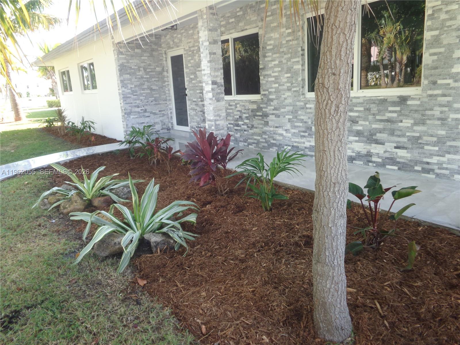 The exterior of a house features a stone facade, a tiled walkway, and a landscaped garden — 1565 Thumb Point Dr, Fort Pierce FL 34949, FORT PIERCE, FL
