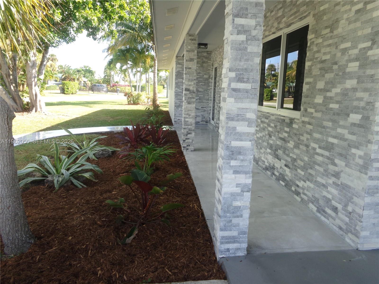 A covered porch features gray stone veneer columns and walls with a tiled floor — 1565 Thumb Point Dr, Fort Pierce FL 34949, FORT PIERCE, FL
