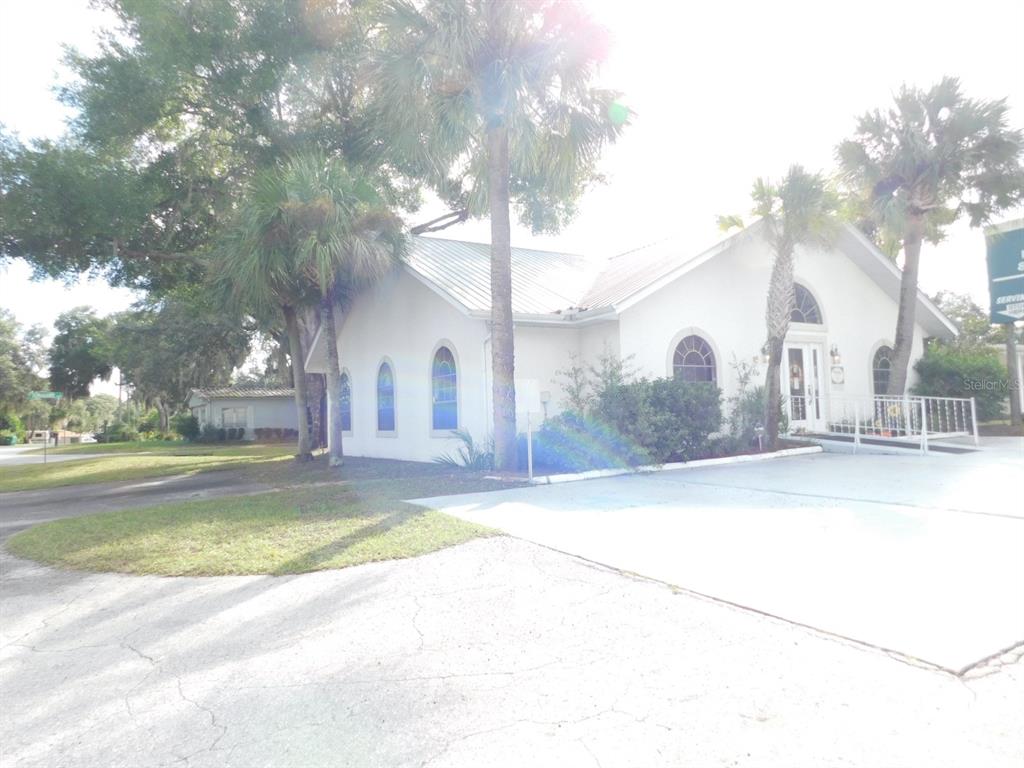 A white building with a metal roof and arched windows sits beside a paved parking lot — 4635 & 4611 N CARL G. ROSE HIGHWAY, HERNANDO, FL