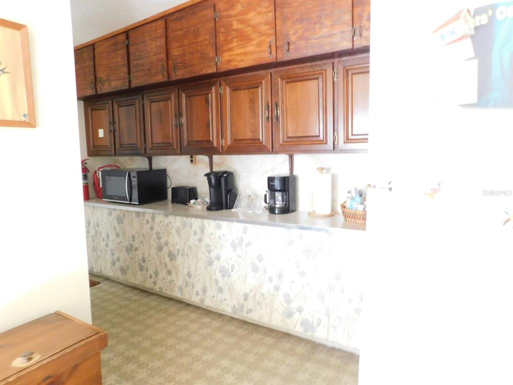 A kitchen features wood cabinets, floral wallpaper, a countertop with appliances, and patterned flooring — 4635 & 4611 N CARL G. ROSE HIGHWAY, HERNANDO, FL