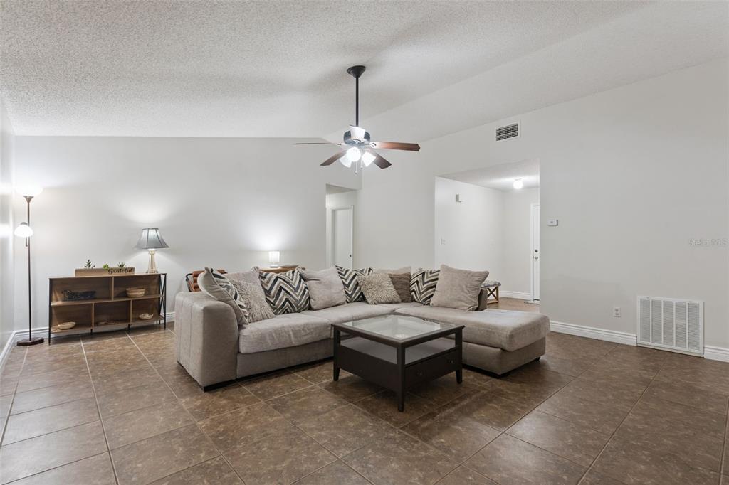 A living room features a sectional sofa, a coffee table, and tile flooring — 15901 SAUSALITO CIR, CLERMONT, FL